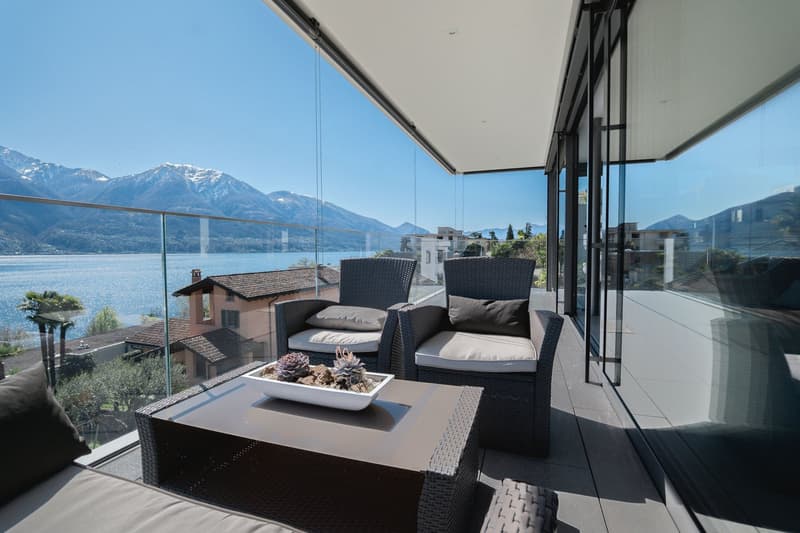 glass railing, two chairs, table with plants, lake view