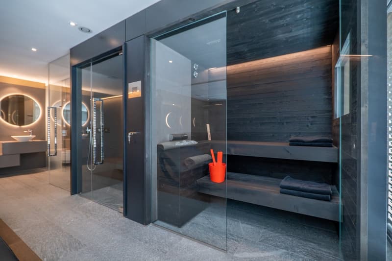 Sauna room with glass walls, wooden benches, and a shower area