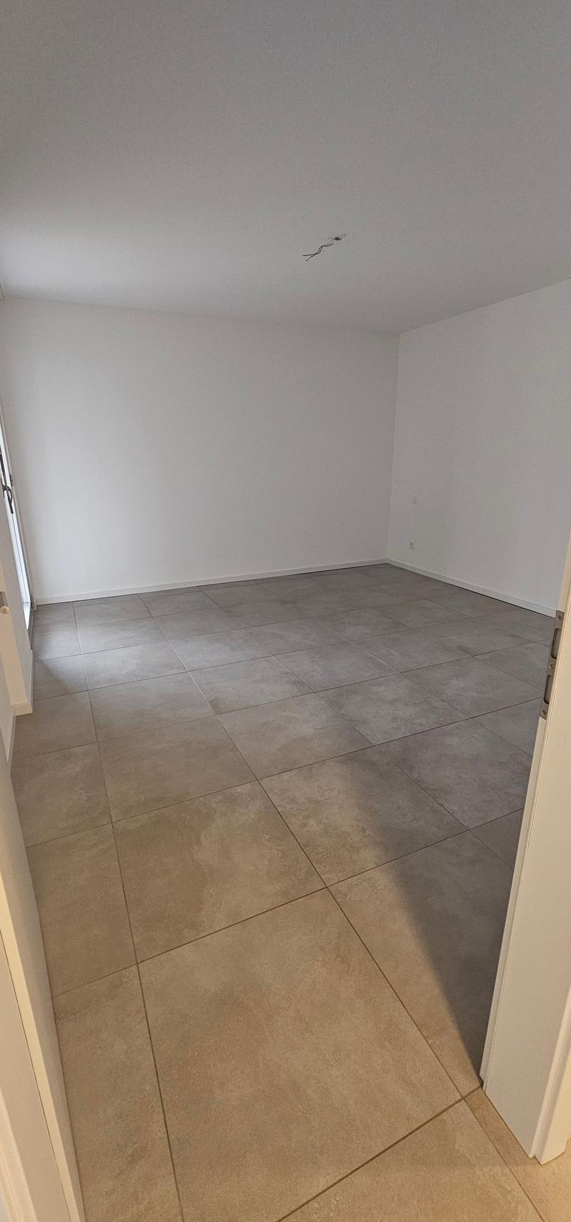 A clean and empty room with a tiled floor and white walls.
