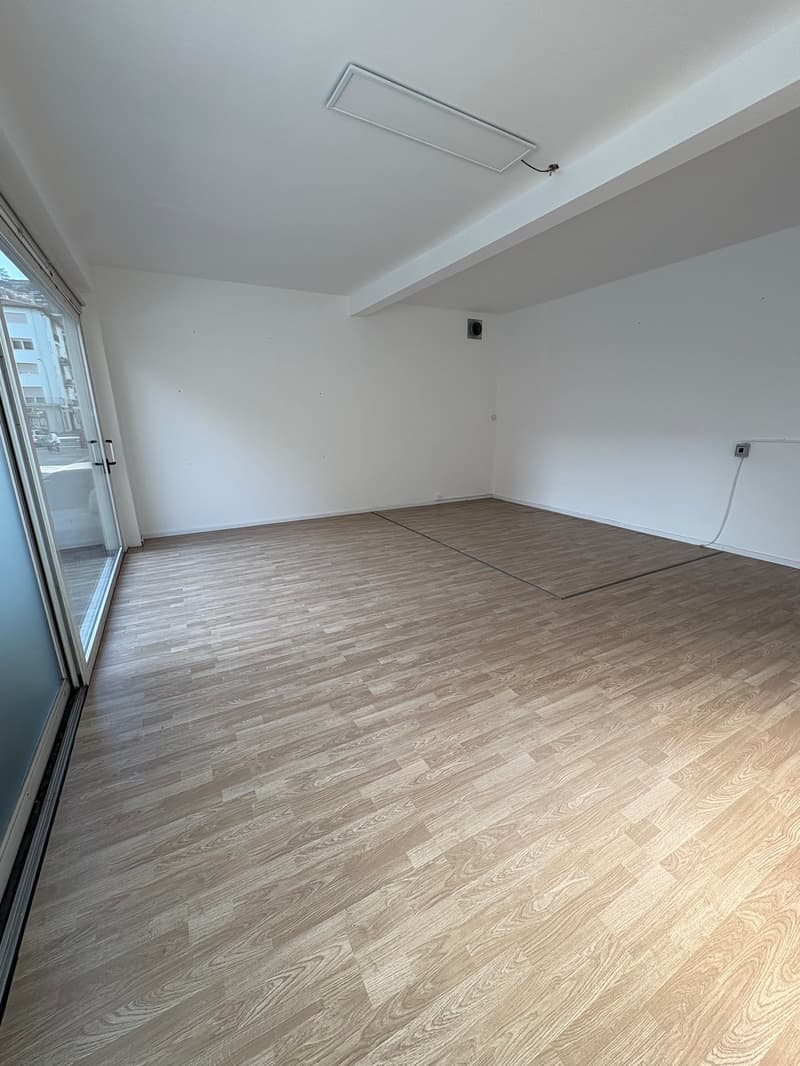 Empty room with hardwood floors, white walls, sliding door, and an open area for layout