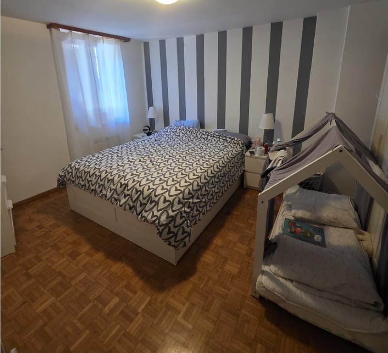 Bedroom with bed, nightstands, lamps, and a playhouse with a mattress.