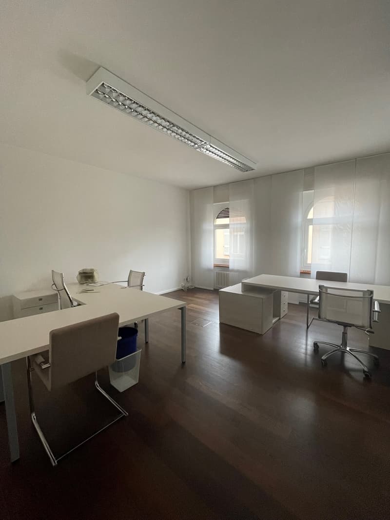 modern office, white walls, wooden floor, large windows, office tables and chairs, radiator, white curtains