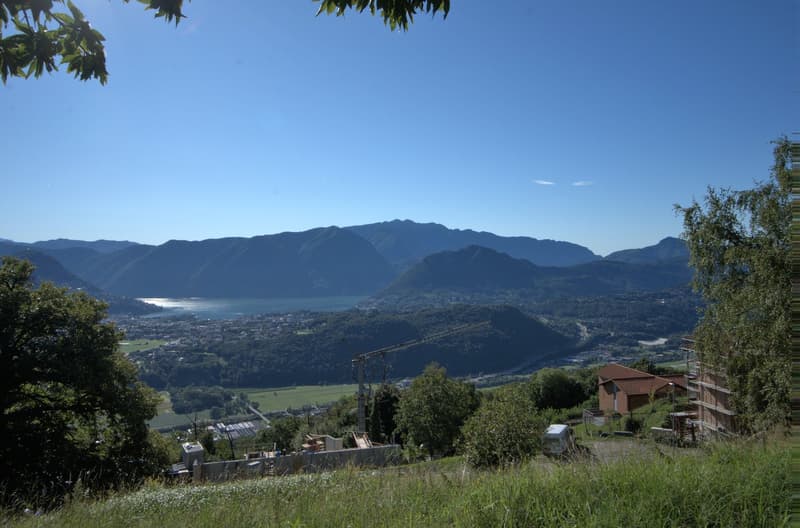 hillside with grass, trees, mountains, lake, town, construction site