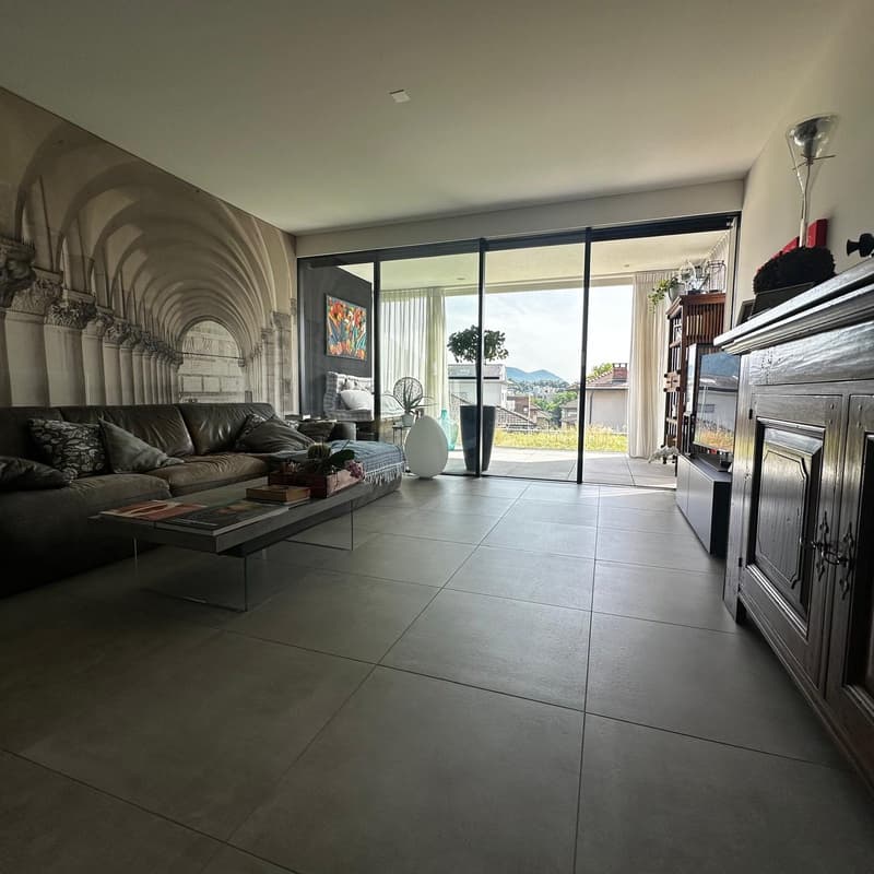 Spacious living room with large windows providing a scenic view, hardwood floors, leather sofa, and a decorative cabinet
