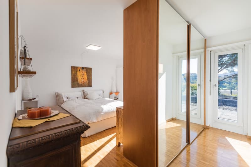 A large bed, wooden nightstand, wooden cabinet, full-length mirror, large glass doors with balcony