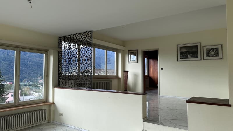 Spacious living room with large windows offering a scenic view, decorative metal partition, hardwood floors, and framed artwork on the walls.