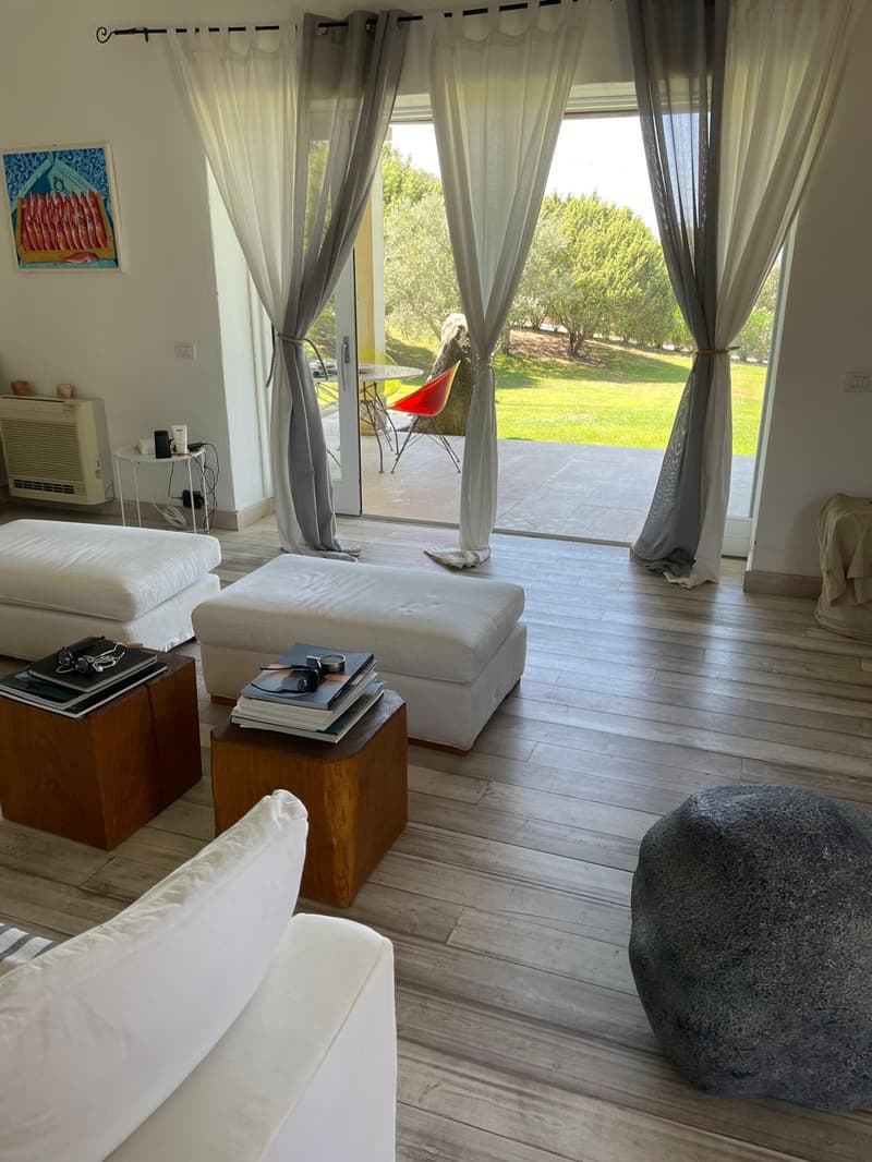 wooden floor, large sliding doors, sofa, armchairs, coffee tables, books, green outdoor space