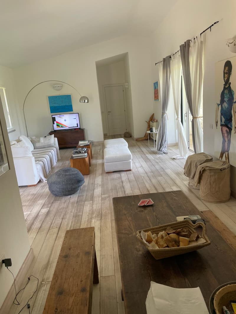 wooden floor, white couch, wooden tables, flat screen TV on stand, artwork