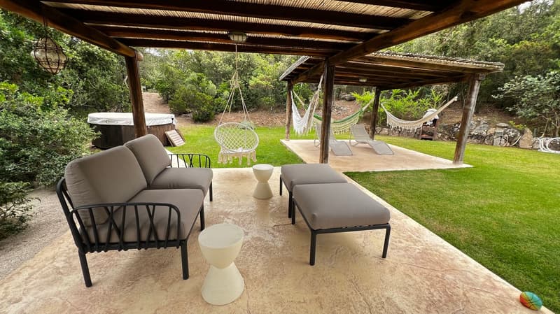 covered patio, outdoor furniture, hammocks, hot tub, green lawn, trees, plants