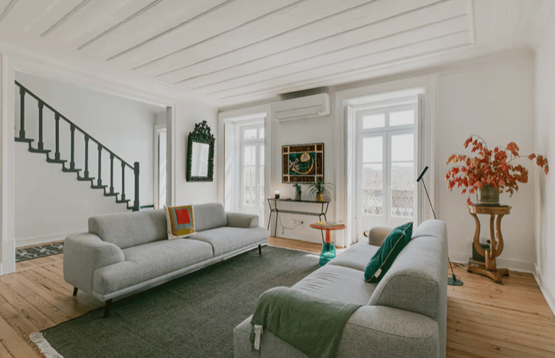 large open room, two sofas, wooden floor, staircase, windows, air conditioning