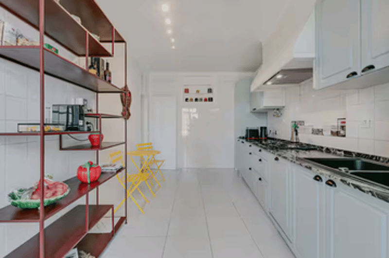 White kitchen with countertops, modern cabinets, cooking appliances, a private washing machine, dining chairs