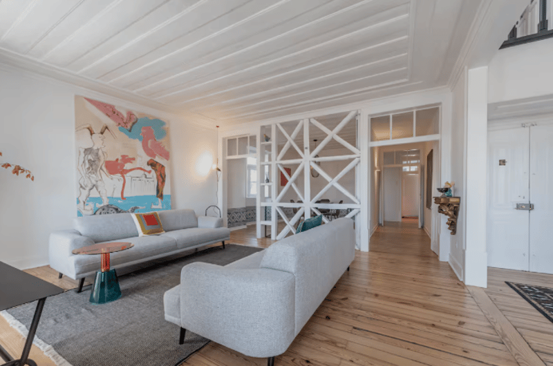 white walls, wooden floor, grey couches, large wall art, glass table, large windows