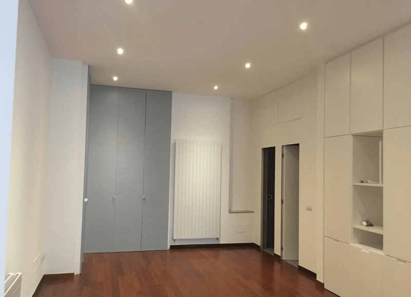 empty room, wooden floor, white walls, built-in wardrobes, radiator, door