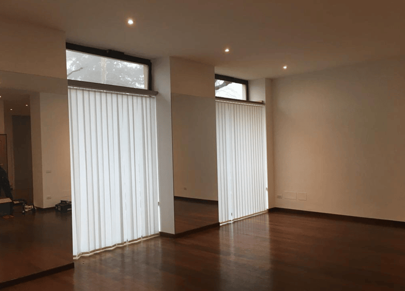 empty room, wooden floor, white walls, large windows with blinds, ceiling lights