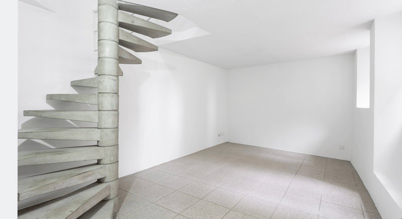 empty room with concrete spiral stairs, empty room, tiles on the floor, outlet in the wall