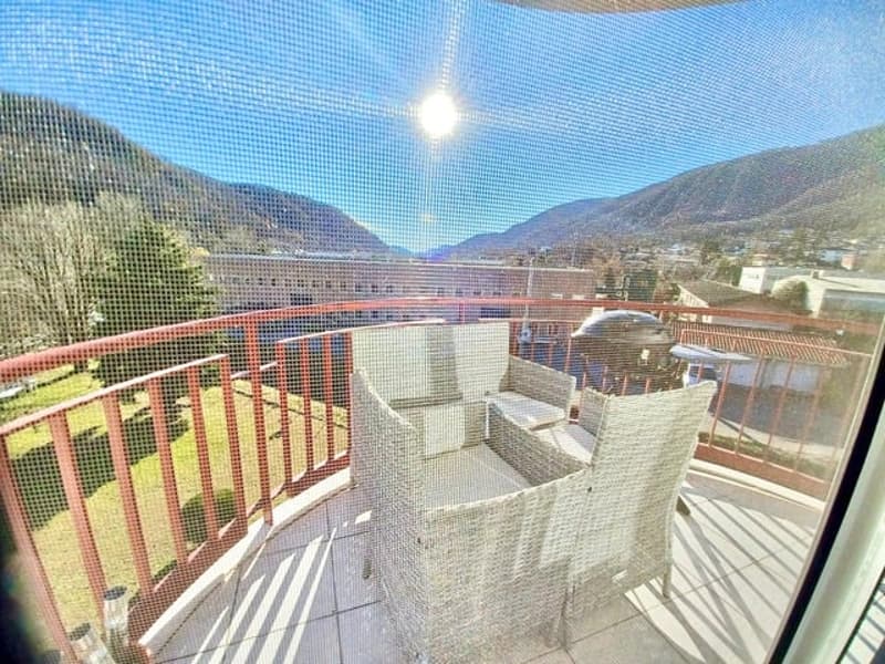 Balcony with two chairs, red railings, and view of the mountains