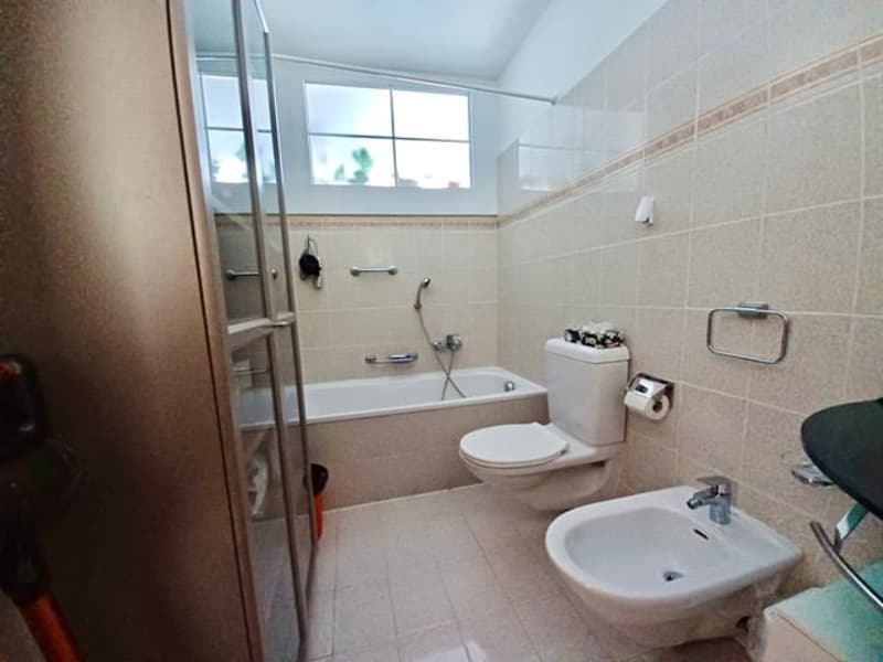 Bathtub, sink, toilet, tiled walls and floor, a shower, showerhead, towel rack, mirror