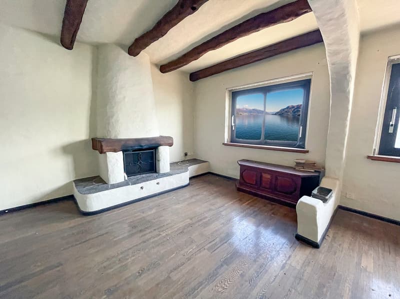 Empty room with fireplace, wooden floor, window with a lake view