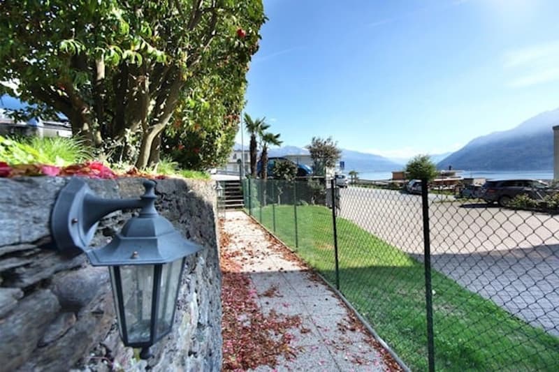 Stone pathway in garden with lamp, fence, green grass, mountain view