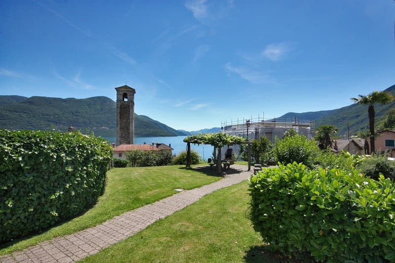 Beautiful view of the surrounding area with mountains, lake, church tower, house, and garden with path