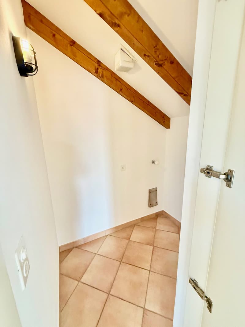 White walls, brown tile flooring, wooden beams, power outlet, switch, door lock, small window