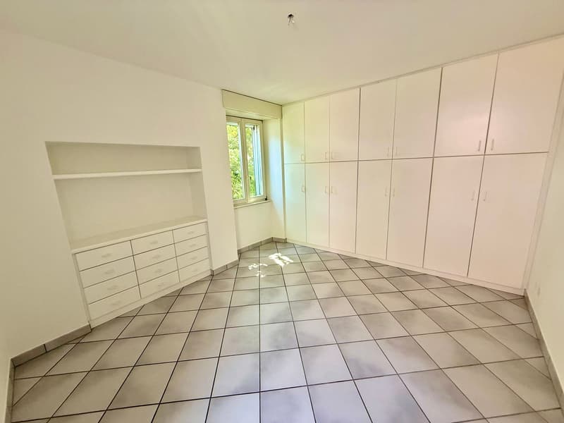 room with tiled floor, white walls, built-in wardrobes, a window with bright light