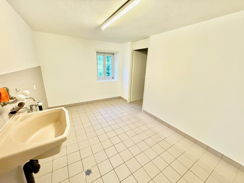 empty bathroom, white tiled floor, white sink, wall-mounted faucet, window, and open door to another room, ceiling lamp