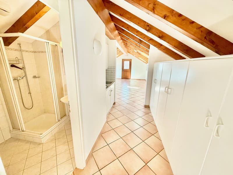 small bathroom with shower, white tiles, white walls, wooden ceiling beams