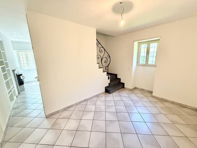 Empty room, tile flooring, white walls, open doorway to another room, staircase, small window
