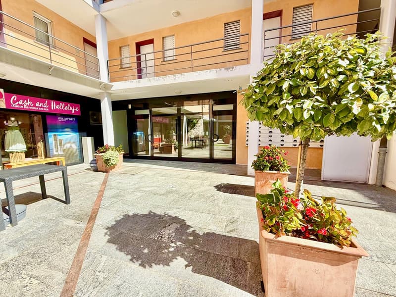 Apartment building, two stories, balconies, glass doors, potted plants, tiled floor, shop in front