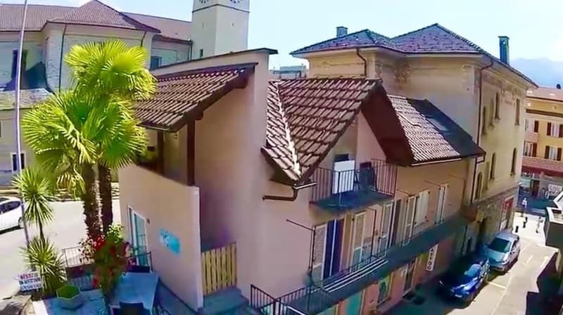 3-story house, brown roof, white walls, balconies, palm trees, cars parked