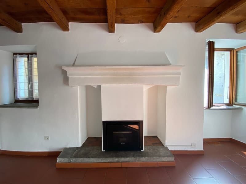 white walls, brown tiled floor, exposed wooden ceiling, fireplace