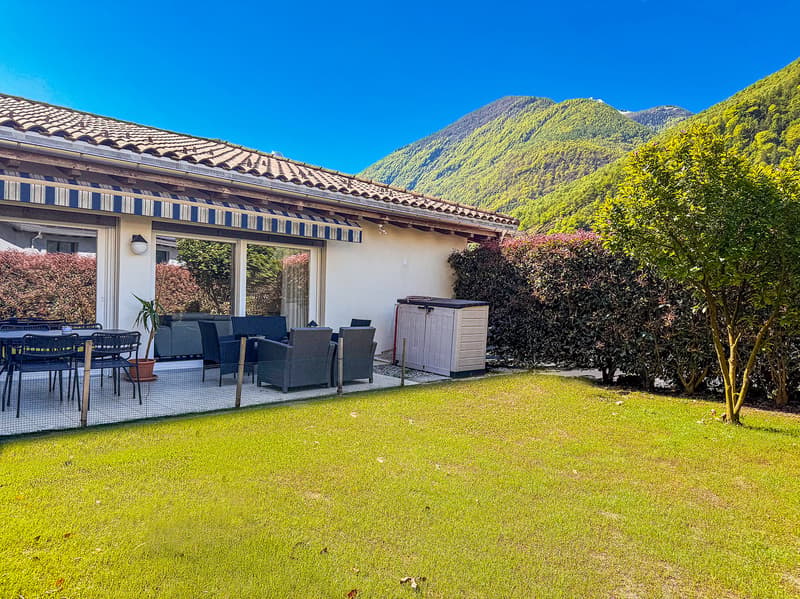 balcony with table and chairs, lush garden, large terrace, green hill in background