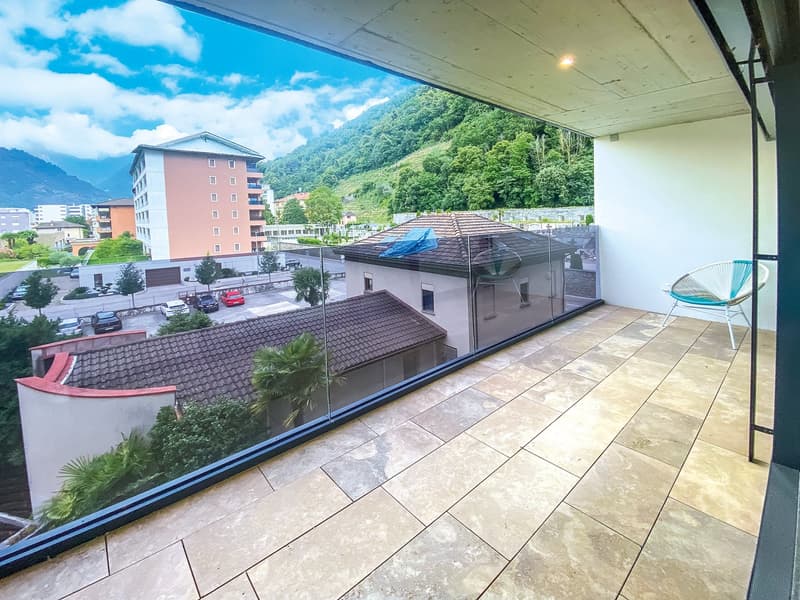 Balcony with panoramic view, glass railing, floored with stone tiles, outdoor chair