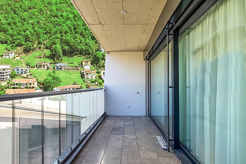 Terrace with tiled floor, full glass railing, sliding glass doors.
