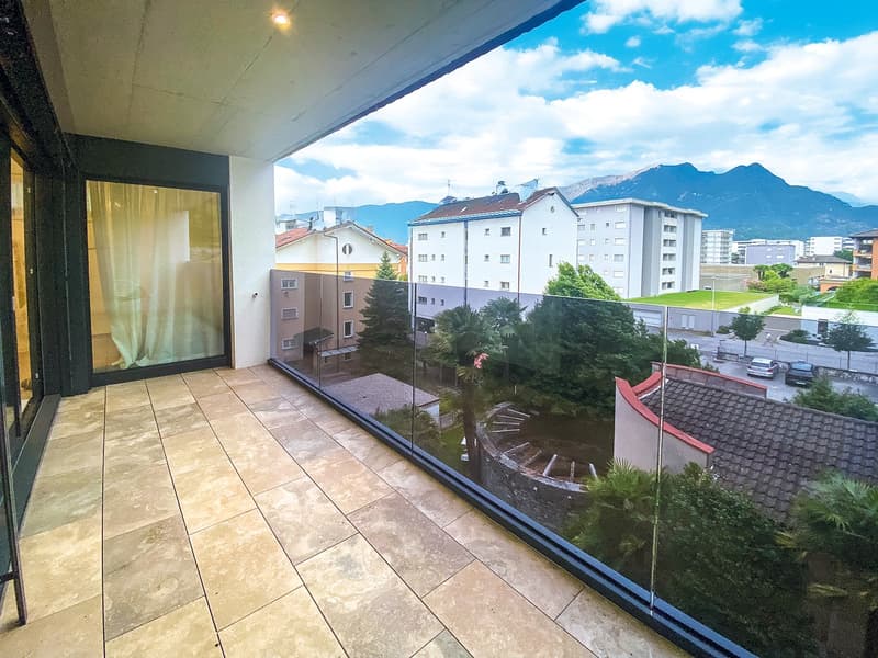 Terrace with glass railing, tiled flooring, view of the city and mountains