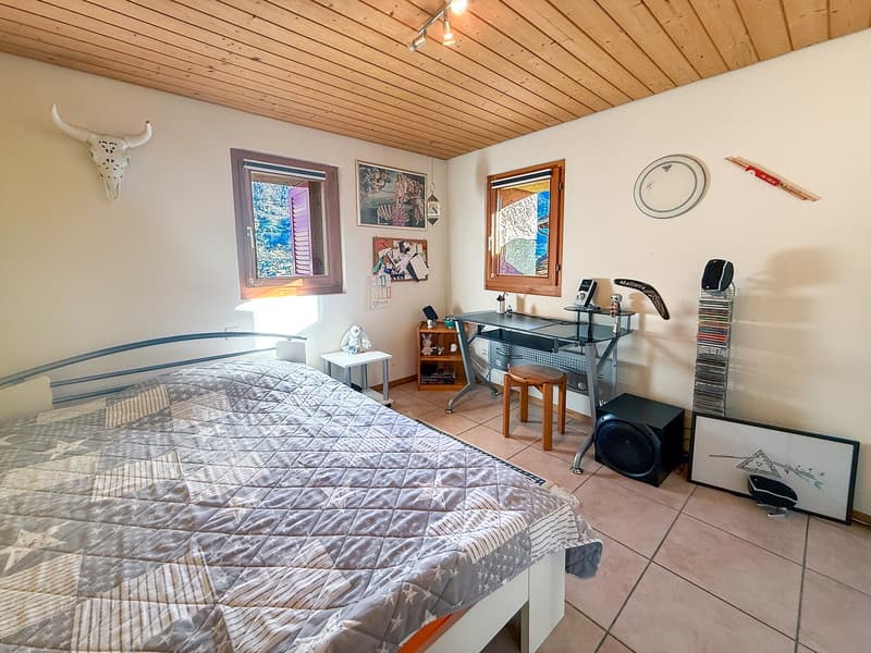 Bed, quilt, window, desk, speaker, bull skull on the wall, picture frame, shelf, stool, small table, clock, disc rack