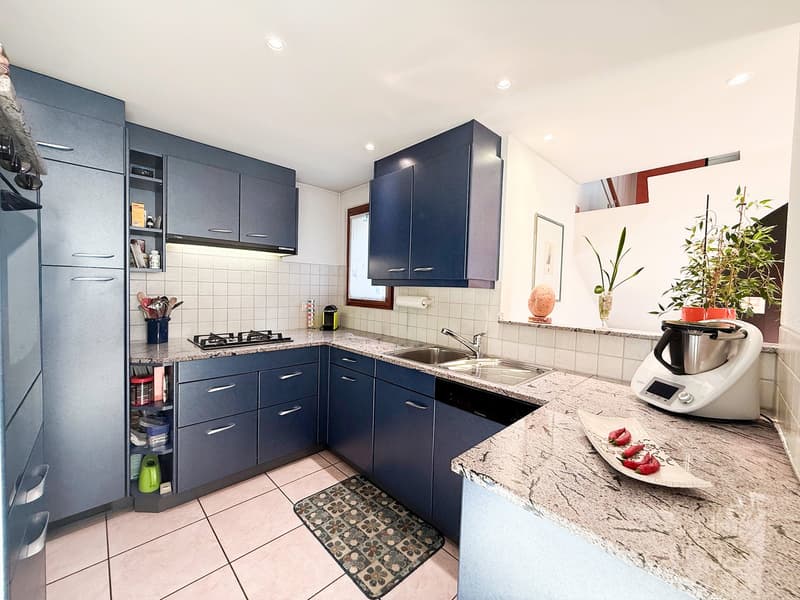 Open kitchen with granite countertops, gas stove, dishwasher, kitchen island, sink with faucet, hanging plants, cabinet, tiled floor, open-plan living space