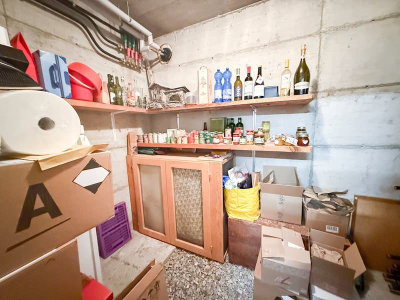 storage room with boxes, shelves with bottles and jars, cabinets with glass doors, floor covered with gravel