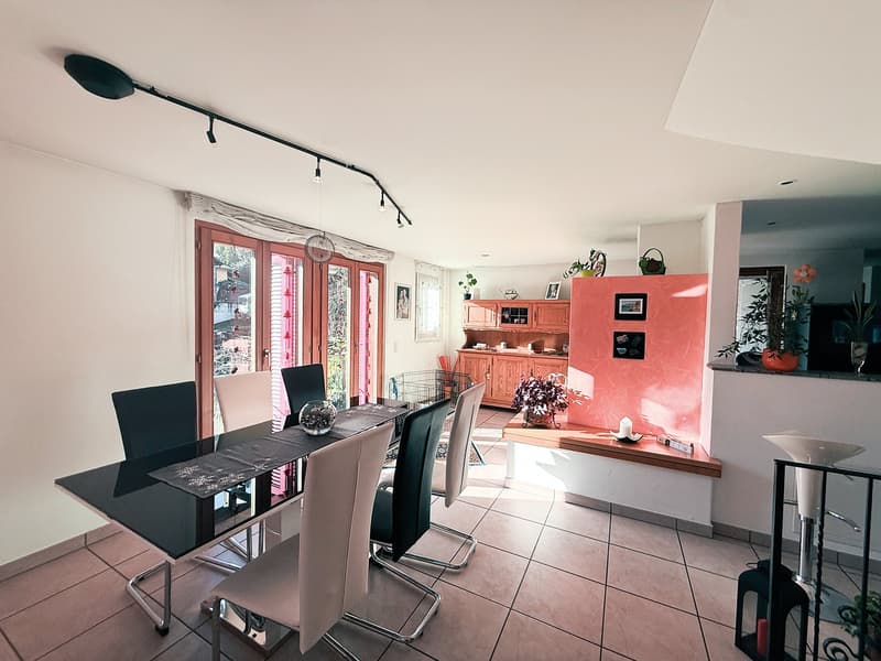 dining area with a modern glass table, several chairs, and a large window overlooking an outdoor space