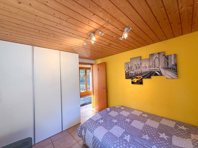 white cabinet, single bed, yellow wall, track lighting, framed pictures, wooden door, rug
