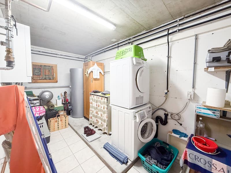 Two washing machines, clothes drying, storage boxes, shelves, table