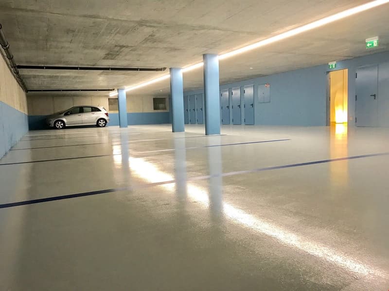 underground parking area, shiny clean floors, single car parked, multiple storage boxes