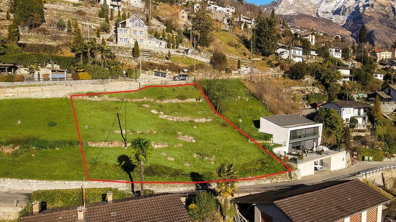 Slope property, hilly terrain, large field, building foundation, other houses in background, mountain view