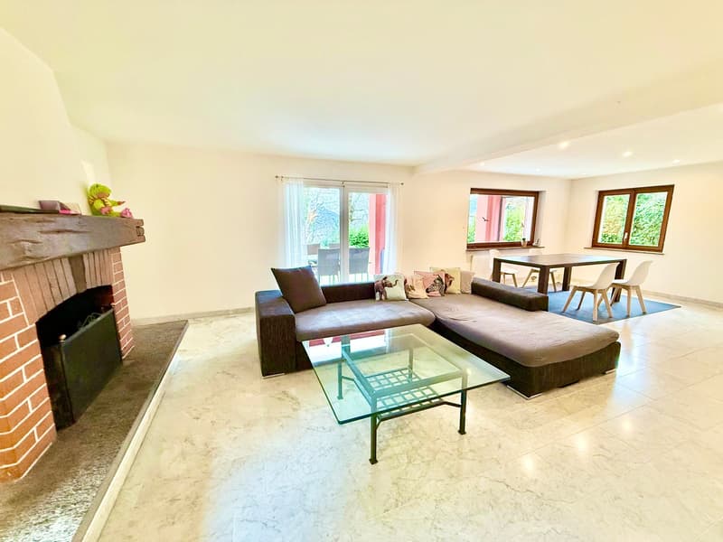 modern design with tiled floor, large sofa with pillows, glass coffee table, dining table with chairs, brick fireplace