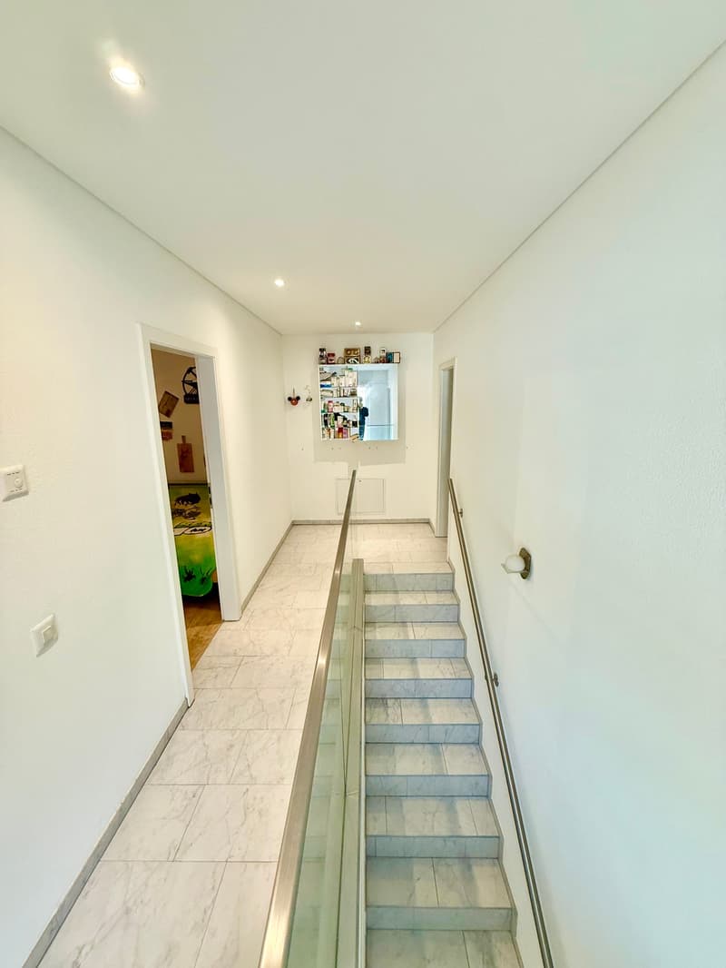 marble flooring, white walls, clear handrails, two doors leading to different rooms, a shelf with various items, an open door leading to a room with a green bed
