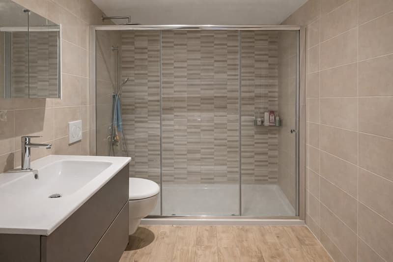 Bathroom with shower, toilet, sink, mirror, wooden floor, tiled walls