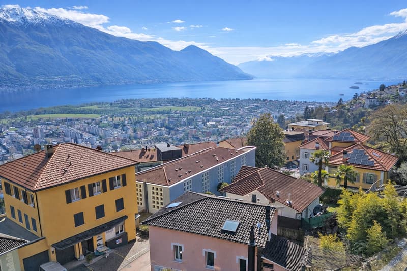 Cluster of multistory homes, red roofs, solar panels, scenic lake view, mountainous landscape