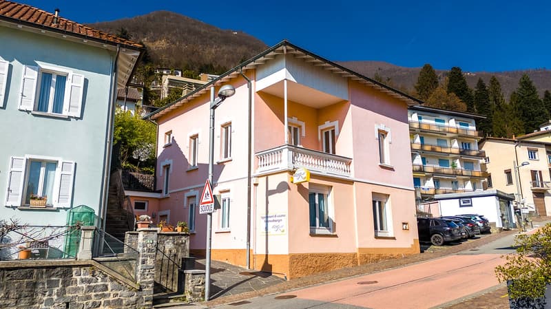 two-story house, light pink facade, white roof, brown steps, white windows, balcony, signboard