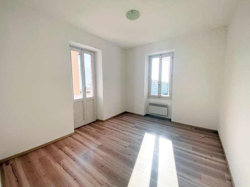 Room has wooden floor, two windows, white walls, empty room
